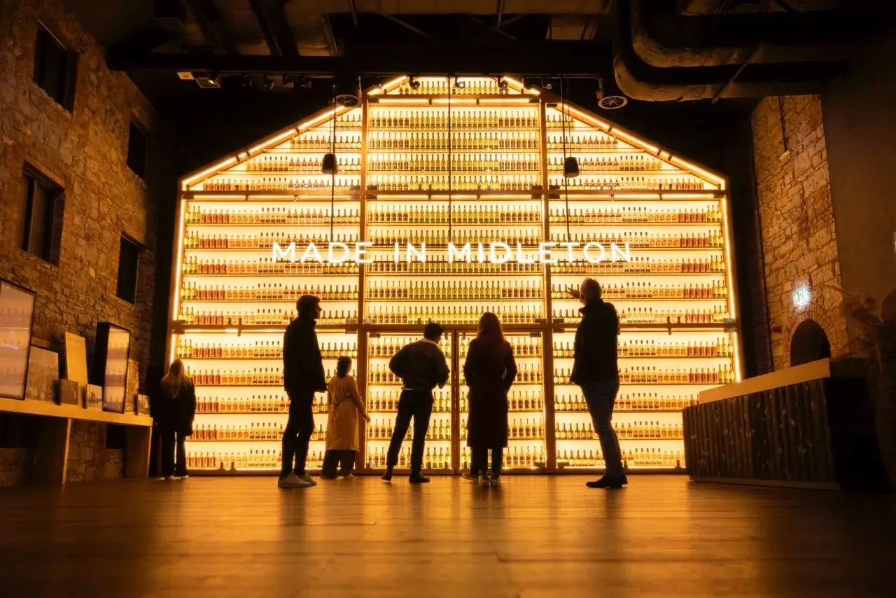 Des visiteurs admirant une impressionnante collection de bouteilles illuminées,
