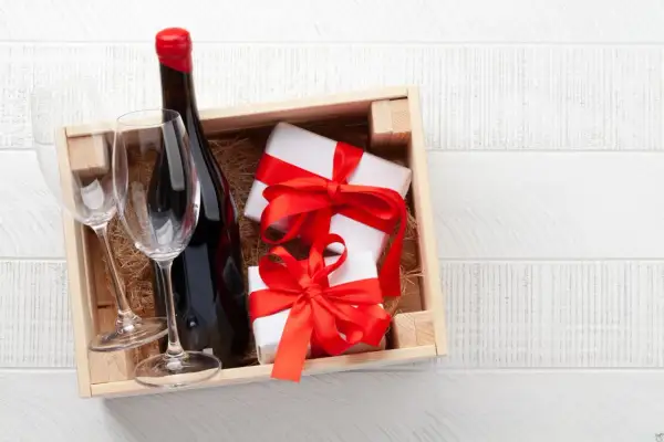 Cadeau gourmand : une bouteille de vin rouge, deux verres et des présents emballés, prêts à être dégustés dans un domaine de Bourgogne.