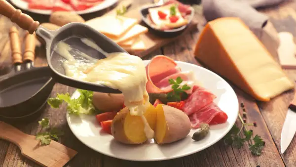 Raclette, le meilleur plat français, avec pommes de terre, charcuterie et fromage fondu. Un délice réconfortant.