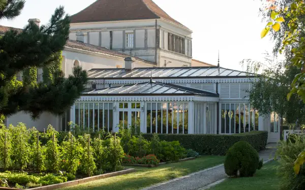 Jardin luxuriant devant une serre élégante, rappelant la beauté du caudalie vignoble.