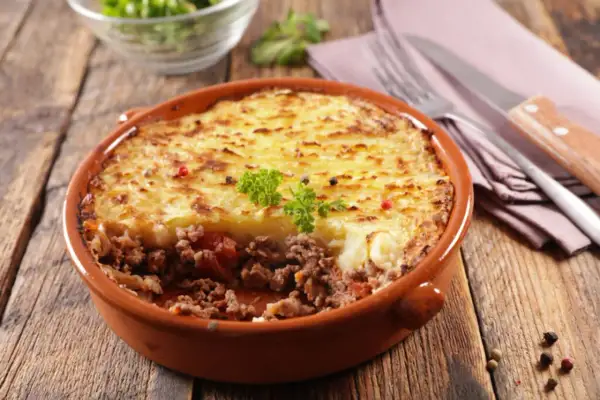 Un plat de hachis parmentier, un classique du repas français, servi dans un plat en terre cuite sur une table en bois.