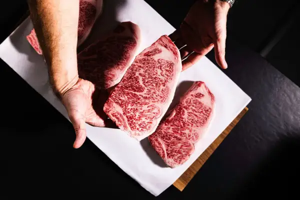 Des mains présentent des steaks de bœuf persillés, marbrés de gras, promettant le meilleur bœuf du monde.