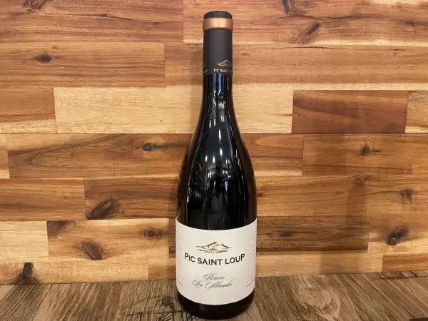 Bouteille de vin rouge du domaine Pic Saint Loup, "Réserve Les Almadies", sur fond de bois.