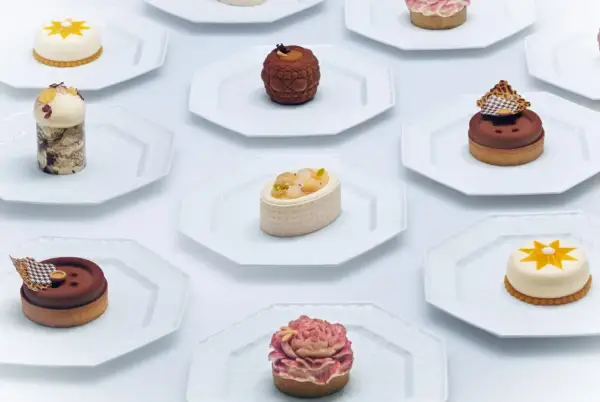 Collection de petits gâteaux raffinés, un véritable produit de luxe alimentaire, présentés sur des assiettes blanches.