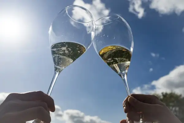 Deux flûtes de champagne pétillant levées en l'air, sous un ciel bleu éclatant. Un toast à Épernay !