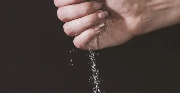 Une main saupoudre du sel, une expression culinaire qui sublime les saveurs.