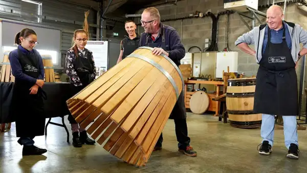 Visite tonnellerie Bourgogne : un maître tonnelier montre un fût en cours de fabrication à des apprentis.