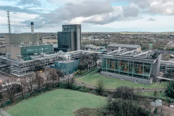 Vue aérienne de la distillerie Midleton, avec ses bâtiments industriels, ses cuves en cuivre visibles à travers une façade vitrée, et un paysage verdoyant en arrière-plan.