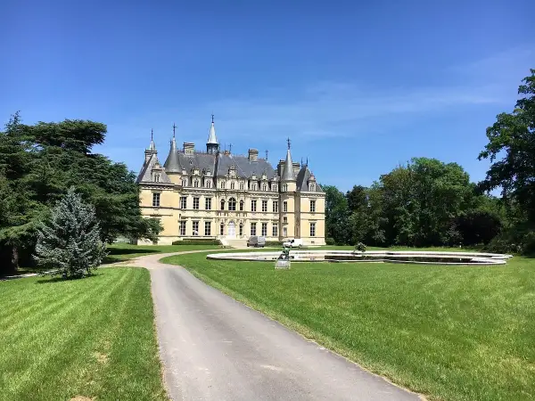 Château majestueux sous un ciel bleu, avec une allée menant à l'entrée. Un lieu idéal pour déguster un champagne Le Gallais.
