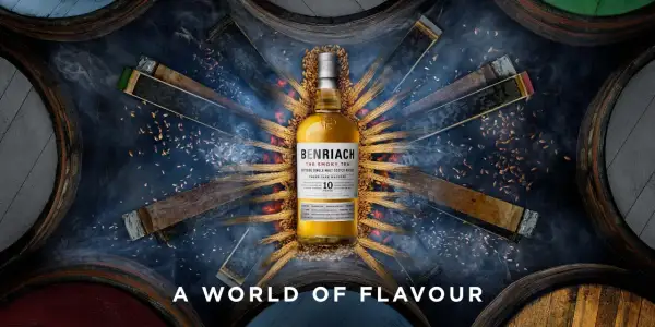 Bouteille de whisky BenRiach The Smoky Ten, entourée de fûts et d'épis de blé, évoquant le savoir-faire de la distillerie.