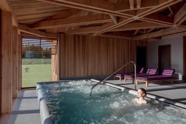 Détente dans un chateau spa à Bordeaux. Une femme profite d'un jacuzzi avec vue sur les vignes.