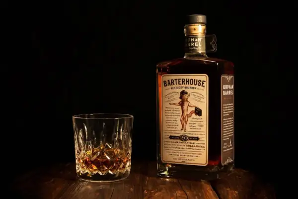 Verre de bourbon ambré et bouteille Orphan Barrel Barterhouse 20 ans. Une dégustation pour apprécier la différence whiskey bourbon.