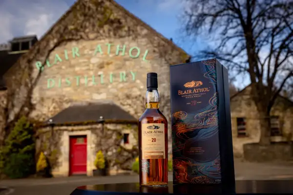 Bouteille de whisky Blair Athol 20 ans et sa boîte devant la distillerie.