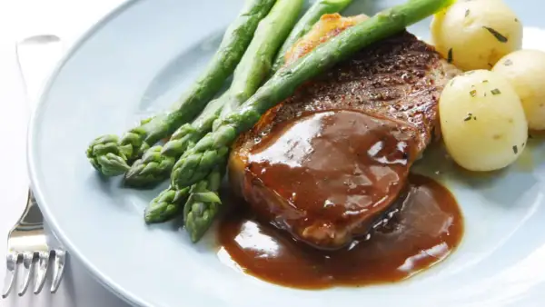 Un délicieux steak servi avec une sauce onctueuse, des asperges croquantes et des pommes de terre nouvelles. Un plat parfait pour un dîner savoureux.